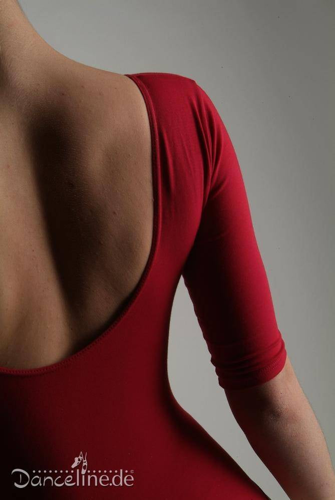 Das Bild zeigt eine Person in einem rückenfreien, roten Ballettanzug APDance 128 Benjamina aus angenehmem Baumwoll-Material. Der Fokus liegt auf dem Rücken und dem rechten Arm der Person. In der unteren linken Ecke erscheint das Logo „Danceline.de“. Der Hintergrund ist schlicht grau.