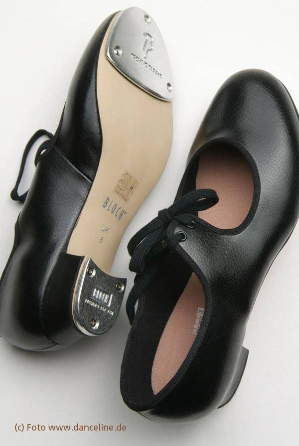 Schwarze Steppschuhe Bloch 330 Timestep liegen auf der Seite, einer zeigt Metallplatten an Ferse und Zehen und die Marke „Bloch“ auf der Kunstledersohle. Die Steppschuhe haben schwarze Schnürsenkel und eine abgerundete Zehenpartie. Foto mit freundlicher Genehmigung von danceline.de.