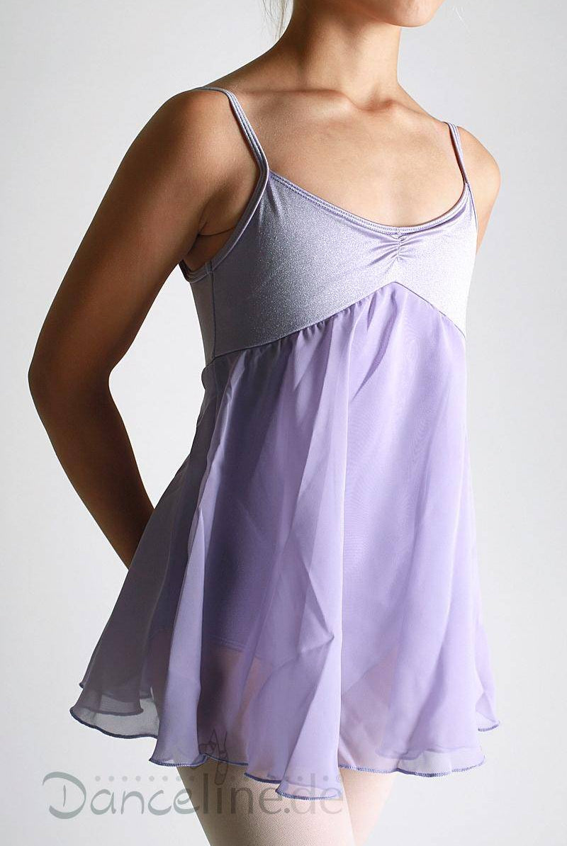 Eine Person trägt den Bloch Kinder Ballettanzug CL7047 Juliet, ein ärmelloses lavendelfarbenes Tanzkleid mit Spaghettiträgern. Das taillierte Oberteil und der Rock im Juliet-Stil schaffen eine elegante Silhouette, während der fließende, halbtransparente Chiffonrock Anmut verleiht. Vor einem schlichten, hellen Hintergrund steht die Person mit entspannt an den Seiten hängenden Armen.