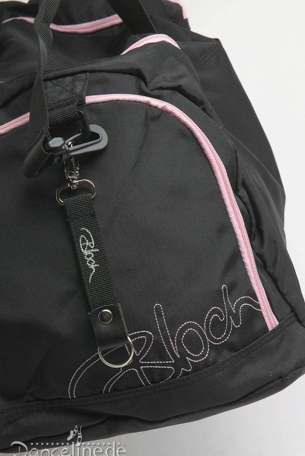 Eine Nahaufnahme der Ballett Tasche Bloch A311 Duffle in Schwarz mit rosa Akzenten und silberfarbener Hardware. Der Markenname „Bloch“ ist in Pink auf die Vordertasche gestickt. In der Nähe des Reißverschlusses ist ein Logo-Tag mit einem Metallclip angebracht. Der Hintergrund ist weiß.