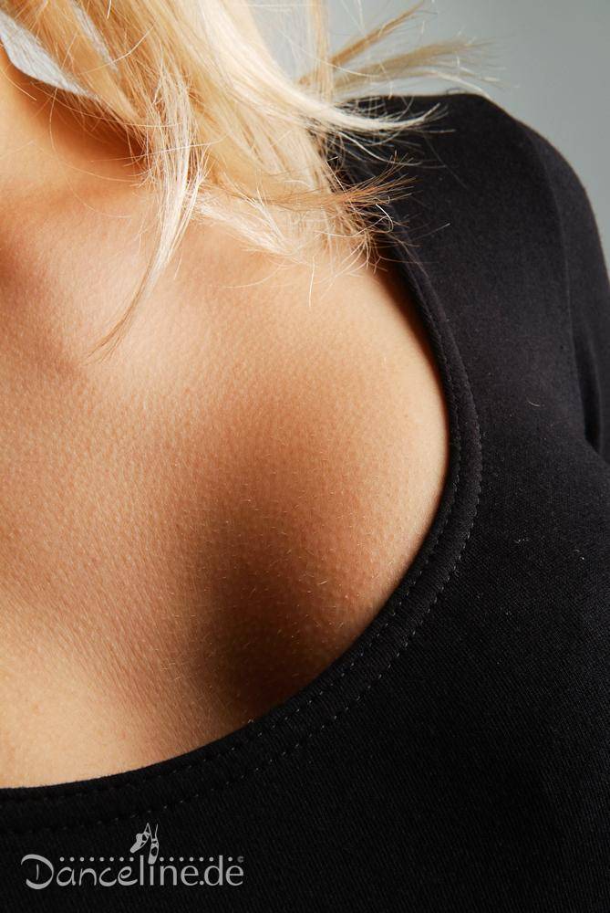 Nahaufnahme einer Frau in einem schwarzen, tief ausgeschnittenen Ballettanzug Bloch L5409 Premier. Der Fokus liegt auf dem Ausschnitt und einem Teil ihrer Brust- und Schulterpartie. In der unteren linken Ecke des Bildes ist das Logo „Danceline.de“ zu sehen. Der Hintergrund ist grau.