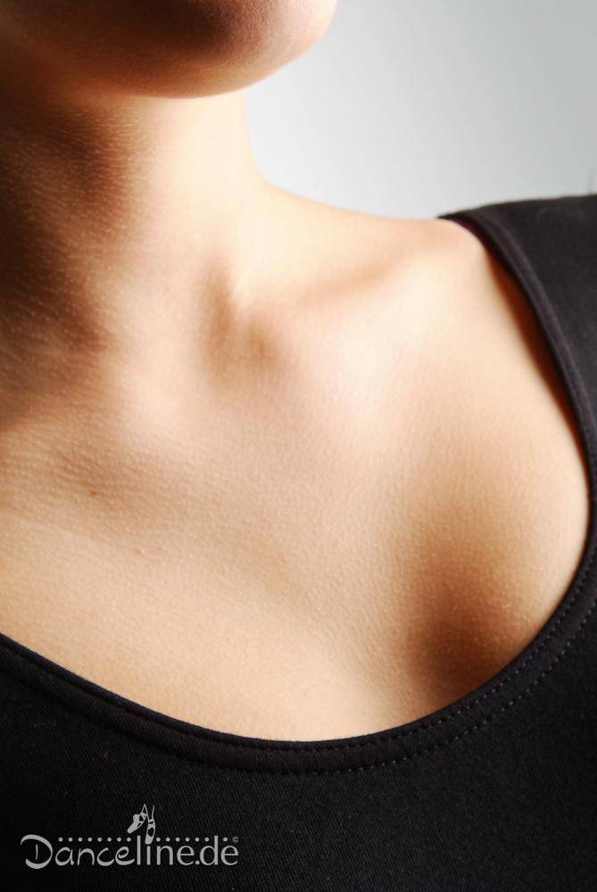 Nahaufnahme einer Person, die einen schwarzen Ballettanzug Bloch L5409 Premier trägt, mit Fokus auf den Halsausschnitt und den Schlüsselbeinbereich. Die Haut hat eine glatte Textur und der Hintergrund ist ein Grauverlauf. Das Logo „Danceline.de“ ist in der unteren linken Ecke des Bildes sichtbar.