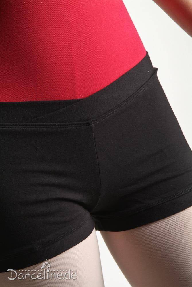 Nahaufnahme einer Person, die ein rotes V-Ausschnitt-Oberteil und die schwarze hoch taillierte Hose Bloch R3614 Pantie von Bloch trägt, die den Bauch und die oberen Oberschenkel zeigt. Das Foto hebt die Kleidungsdetails und die Passform hervor und betont den auffälligen Kontrast zwischen den roten und schwarzen Stoffen.