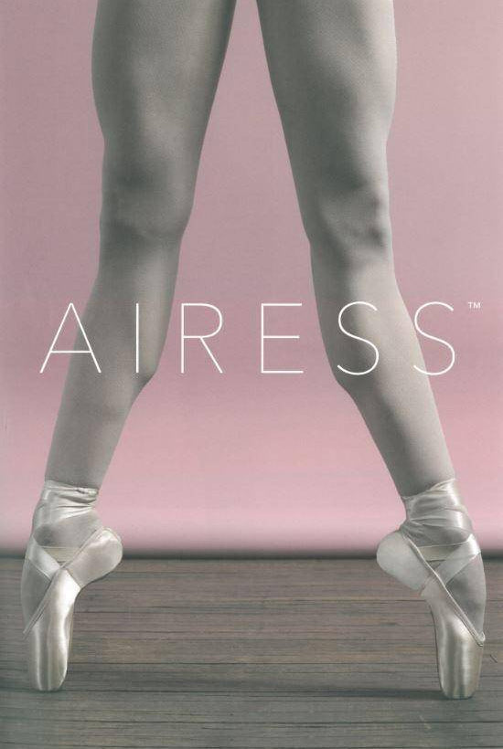 Die Beine einer Tänzerin in hellgrauen Strumpfhosen und Spitzenschuhen stehen auf einem Holzboden vor einem rosa Hintergrund mit Farbverlauf. Die Worte „Spitzenschuhe Capezio 1134B Airess Tapered“ sind in großen weißen Buchstaben über die Beine der Tänzerin geschrieben und betonen die Präzision des Schafts 6,5 und des Breite Form-Designs.