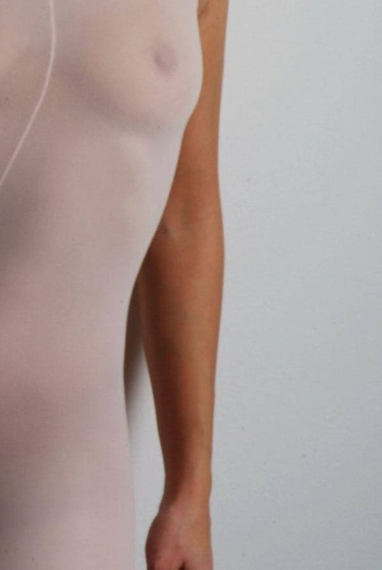 Eine Person trägt die Ballettstrumpfhose Capezio 1818 B-Tight in Hellrosa vor einem schlichten Hintergrund. Das Bild konzentriert sich auf Oberkörper und Arme und zeigt den figurbetonten und leicht durchsichtigen Stoff, der fast an eine figurbetonte Strumpfhose erinnert. Der Markenname Capezio ist mit diesem Produkt verbunden und die Website „danceline.de“ erscheint unten im Bild.