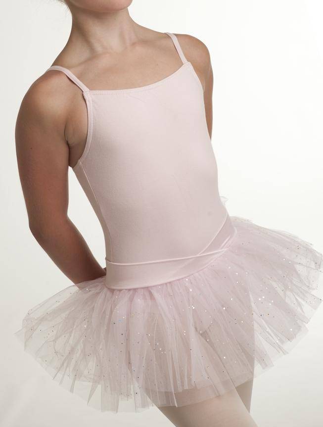 Eine junge Tänzerin ist von den Schultern abwärts zu sehen und trägt einen hellrosa Kinder-Ballettanzug Capezio 9814C Jadica mit Spaghetti-Träger und einen dazu passenden, glitzernden Tüllrock. Die Hände der Tänzerin sind hinter dem Rücken vor einem schlichten weißen Hintergrund positioniert.
