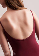Nahaufnahme einer Person mit langen braunen Haaren, die Rücken und Schultern im Ballettanzug Capezio CC101 Edisa von Capezio zeigt. Das burgunderfarbene Oberteil hat Spaghetti-Träger mit dünnen Trägern und einen tiefen Rückenausschnitt und verkörpert die Eleganz eines Ballettensembles. Der Hintergrund ist schlicht und hell.