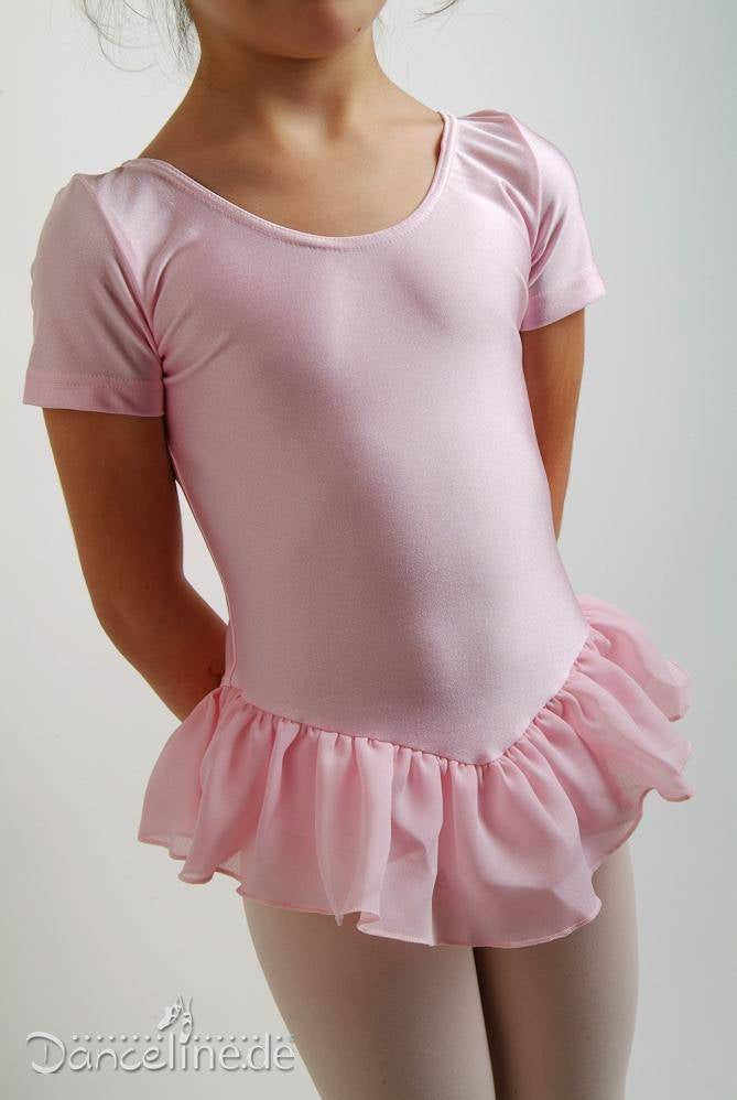 Ein kleines Kind in einem rosa Ballerina-Outfit steht vor einem schlichten Hintergrund. Der hochwertige **Danceries Kinder Ballettanzug Danceries F05L Laurasson EL** besteht aus einem kurzärmligen Ballettanzug mit Rüschenrock und hellen Strumpfhosen. Die Hände des Kindes ruhen auf den Hüften.