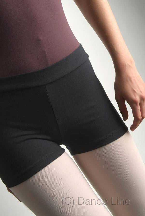 Eine Person, die einen lilafarbenen Turnanzug, schwarze Tanzshorts und weiße Strumpfhosen trägt, ist von den Schultern bis zur Mitte des Oberschenkels zu sehen, wobei nur die rechte Hand sichtbar ist. Der Hintergrund ist ein schlichtes Hellgrau. (C) Danceries ist in der unteren rechten Ecke aufgedruckt und hebt die Hose Danceries G33 Angie für ihr stilvolles und schickes Ensemble hervor.
