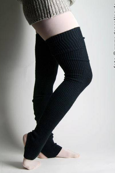 Eine Person in schwarzen, gerippten Intermezzo Stulpen Intermezzo 2657 Stulpimax steht mit übereinandergeschlagenen Beinen. Dazu trägt sie einen beigefarbenen Strickpullover. Der Hintergrund ist schlicht und hell. Auf der rechten Seite ist der Text „foto © www.dance4line.de“ zu sehen.