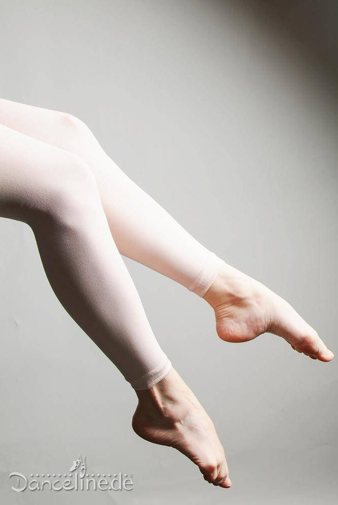 Ein Paar Füße in der rosa Ballettstrumpfhose Rumpf 106 Sans der Marke Rumpf hebt sich anmutig von einem grauen Hintergrund ab. Die Beine sind an den Knien leicht gebeugt und das Bild wurde von der Seite aufgenommen, wodurch die glatte Textur und die sehr dehnbare Passform der Strumpfhose hervorgehoben werden.