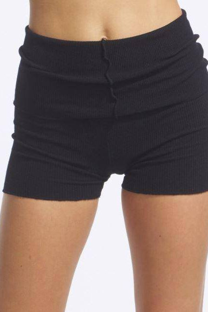 Eine Person trägt die Wärmehose TempsDanse Jordan, schwarze Rippshorts mit Rollbund. Der Fokus liegt auf der Körpermitte und den Beinen, wodurch die perfekte Passform betont wird. Der Hintergrund ist schlicht weiß.