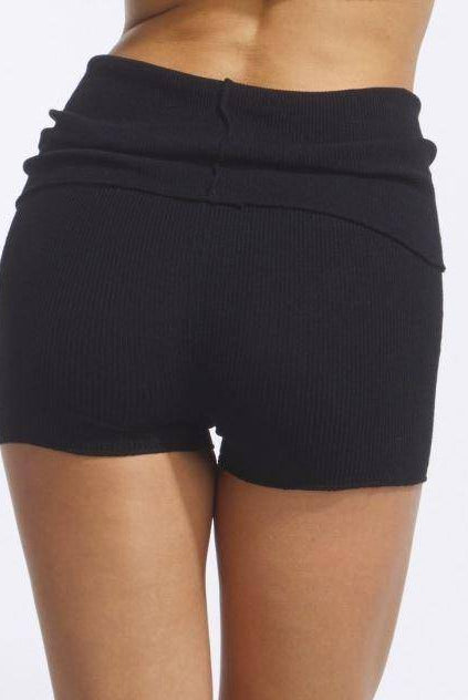 Das Bild zeigt die Rückenansicht einer Person, die die Wärmehose TempsDanse Jordan von Temps Danse trägt. Die Shorts sind gerippt, hoch tailliert und dehnbar, sodass sie eng am Körper anliegen. Der schlichte weiße Hintergrund hebt die Details dieser stylischen Shorts hervor.