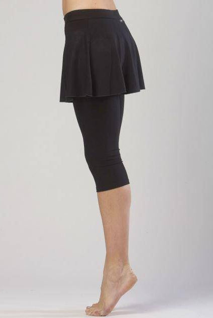 Eine Person steht auf den Zehenspitzen und trägt die Hose TempsDanse Zazou von Temps Danse, einen schwarzen Skort aus elastischer Viskose. Die Person ist vom Bauch bis zu den Füßen vor einem schlichten, hellen Hintergrund zu sehen.