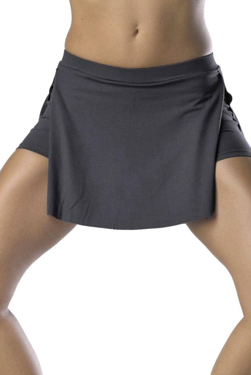 Eine Person steht mit gespreizten Beinen und trägt den Short-Rock TempsDanse Vison von Temps Danse in Dunkelgrau. Dieser Jugendrock verfügt über integrierte Strumpfhosen, die optimale Bewegungsfreiheit bieten. Der Skort zeigt einen kurzen Rocküberzug mit sichtbaren Shorts darunter, vor einem schlichten weißen Hintergrund.