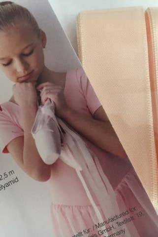 Eine Rumpf Satinbänder Rumpf RU11 Produktverpackung mit einem Bild eines jungen Mädchens in einem Ballett-Outfit, das rosa Spitzenschuhe hält. Die Verpackung enthält breite hellrosa Satinbänder, die als 2,4 cm breit und 2,5 Meter lang beschrieben werden und aus Seide und Polyamid bestehen.