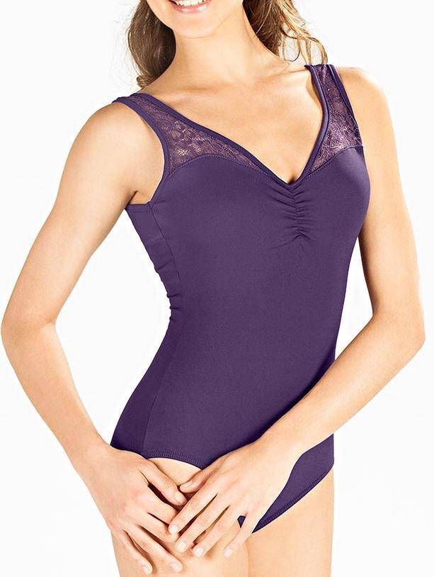 Eine Frau trägt den SoDanca Ballettanzug E10910 Melanie, einen violetten ärmellosen Ballettanzug mit elastischer Spitze am Ausschnitt, und steht mit locker vor sich gefalteten Händen vor einem schlichten weißen Hintergrund.