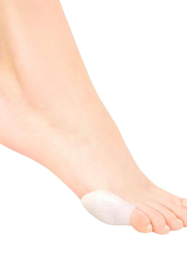 Nahaufnahme eines Fußes mit einem Silikon Blasenschutz Rumpf 1431 Silky-Pad an der Seite des großen Zehs. Das Pad scheint dem Ballenzeh, einer knöchernen Beule am Gelenk an der Basis des großen Zehs, Polsterung und Halt zu bieten. Ideal für Spitzentänzerinnen oder alle, die zusätzlichen Schutz gegen Blasen benötigen.