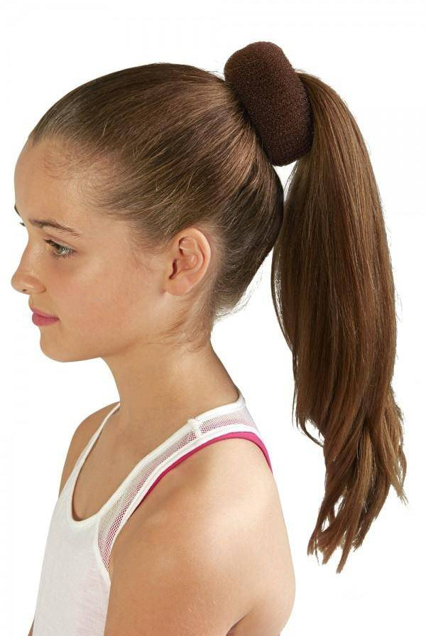 Im Profil ist ein junges Mädchen mit langen braunen Haaren abgebildet, ihr Haar ist zu einem hohen Pferdeschwanz gestylt und mit einem wiederverwendbaren Duttkissen Bloch A0803 der Marke Bloch befestigt. Sie trägt ein weißes Tanktop mit dünnen rosa Trägern. Der Hintergrund ist schlicht und weiß.