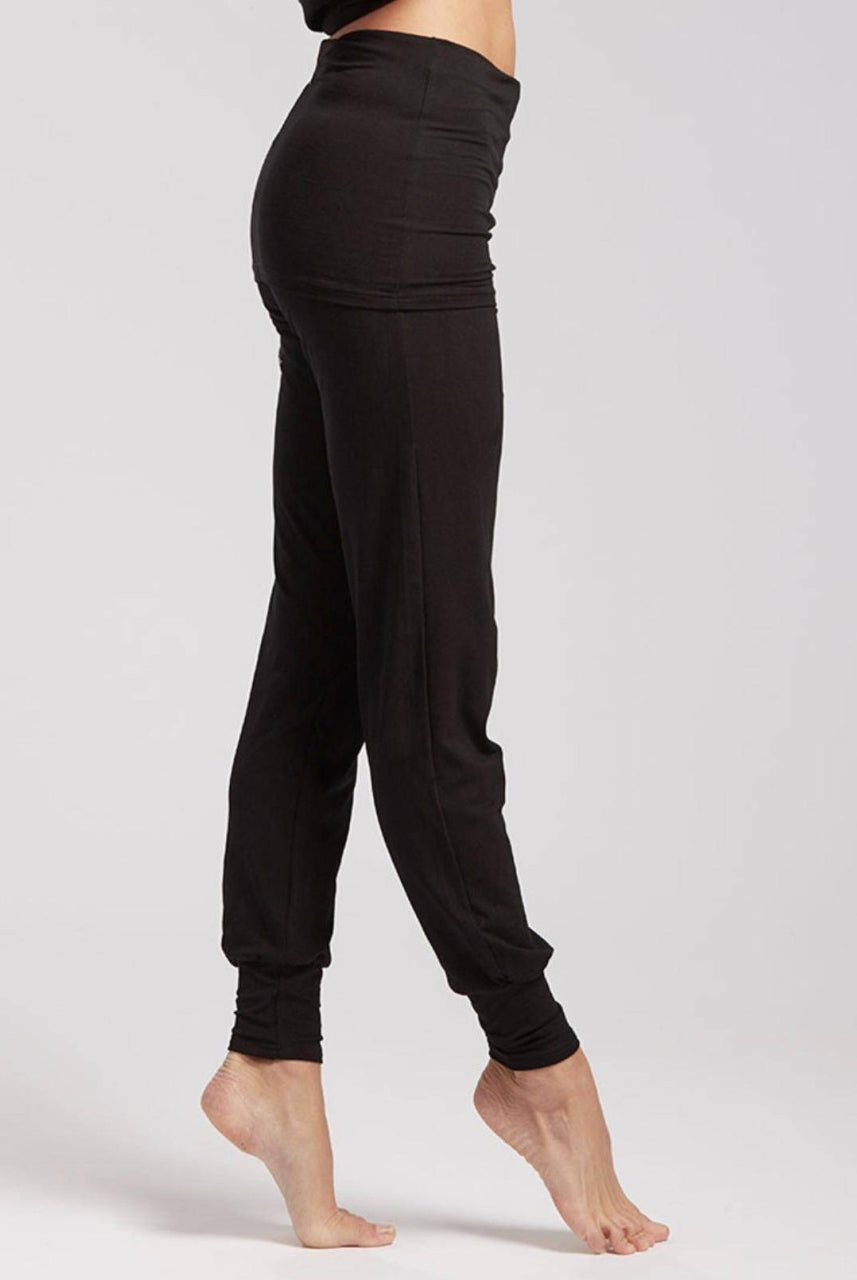 Eine Person steht auf den Zehenspitzen und präsentiert eine eng anliegende Yogahose TempsDanse Alto in Schwarz, perfekt für Pilates. Der Hintergrund ist schlicht und hell und betont die Silhouette und die Details der Hose von Temps Danse. Die Füße der Person sind nackt und die Hose reicht bis zu den Knöcheln.