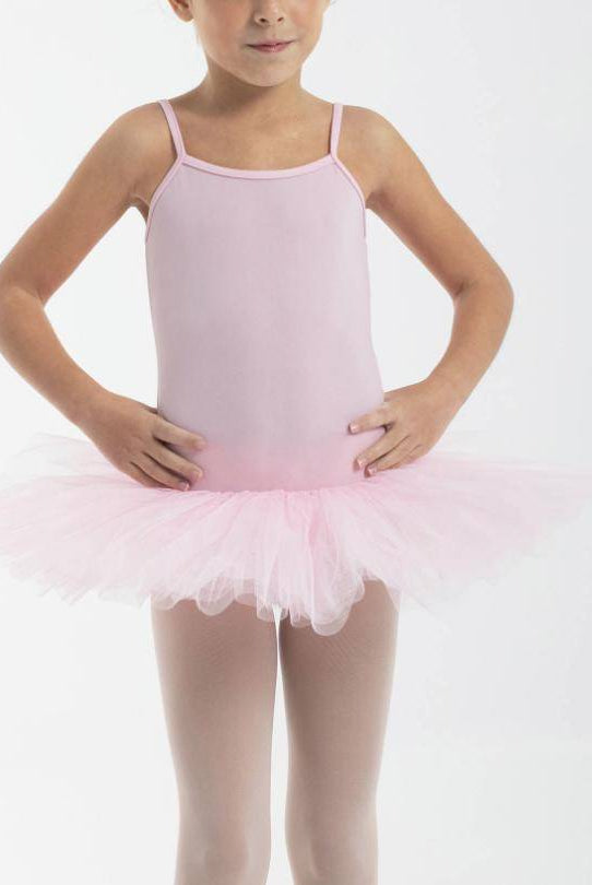 Ein junges Mädchen trägt das Tutu Intermezzo 3152 von Intermezzo, einen hellrosa Ballettanzug mit Spaghettiträgern und einem dazu passenden Basic-Tutu aus vier Lagen Tüll. Ihre Hände sind auf ihren Hüften abgelegt und sie steht vor einem schlichten weißen Hintergrund.