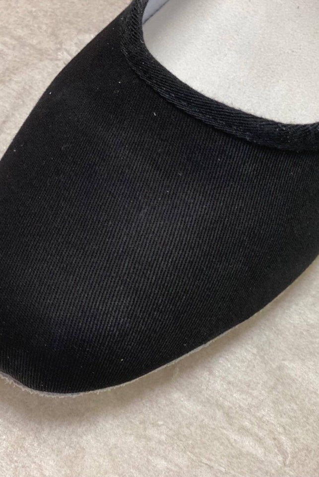 Nahaufnahme eines Charakterschuhs Danceries Z66 für Damen mit abgerundeter Spitze, aus glattem schwarzem Stoff. Der Schuh, der den Standards der Royal Academy of Dance entspricht, ruht auf einer hellen, strukturierten Oberfläche.
