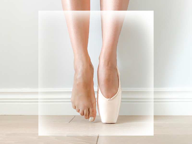 Frontansicht von zwei Füßen auf Spitze. Der rechte Fuß hat einen Spitzenschuh an, der linke Fuß nicht.