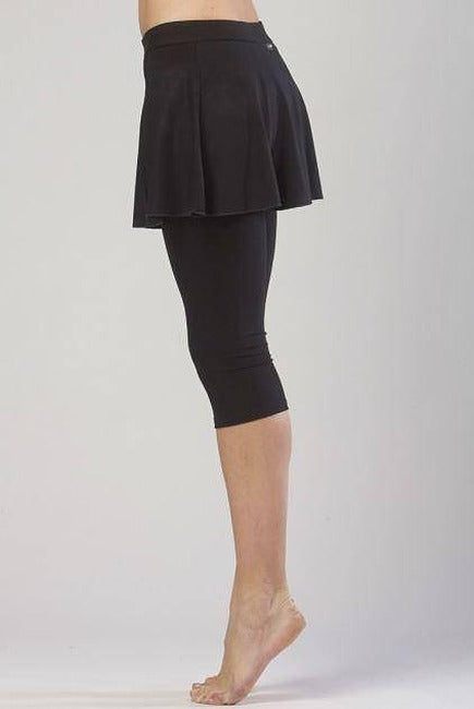 Eine Person steht auf den Zehenspitzen und trägt die Hose TempsDanse Zazou von Temps Danse, einen schwarzen Skort aus elastischer Viskose. Die Person ist vom Bauch bis zu den Füßen vor einem schlichten, hellen Hintergrund zu sehen.