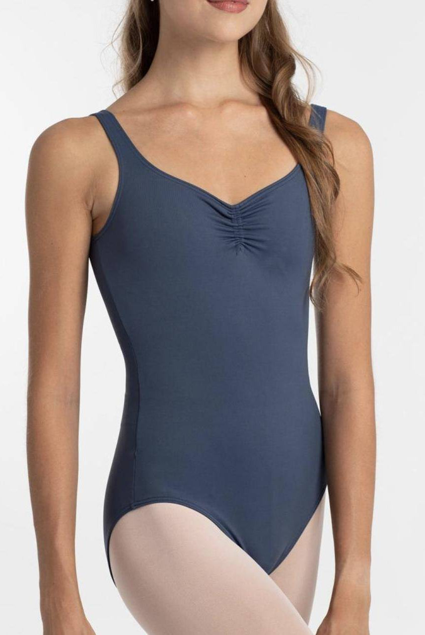 Eine Person trägt den Intermezzo Ballettanzug 31232 Marya in Blau mit hochwertigen Details wie einer gerüschten Vorderseite und hellen Strumpfhosen. Der Hintergrund ist schlicht weiß und das Gesicht der Person ist nicht vollständig sichtbar.