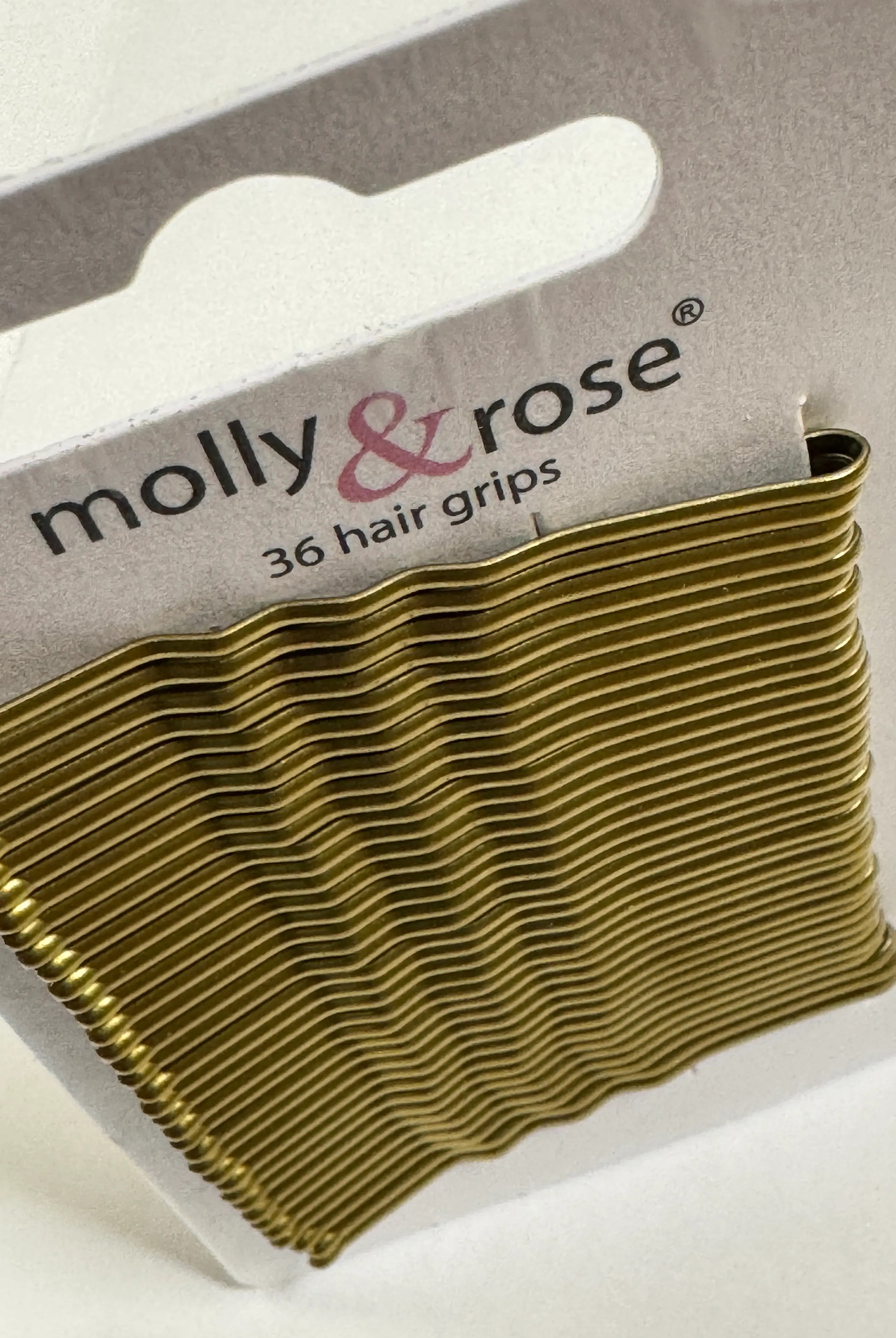 Eine Packung mit 36 goldenen Haarspangen, präsentiert in einem Kartonhalter mit der Aufschrift „Intermezzo“ unter dem Produktnamen „Haarklemmen Intermezzo 7492 Molly“.