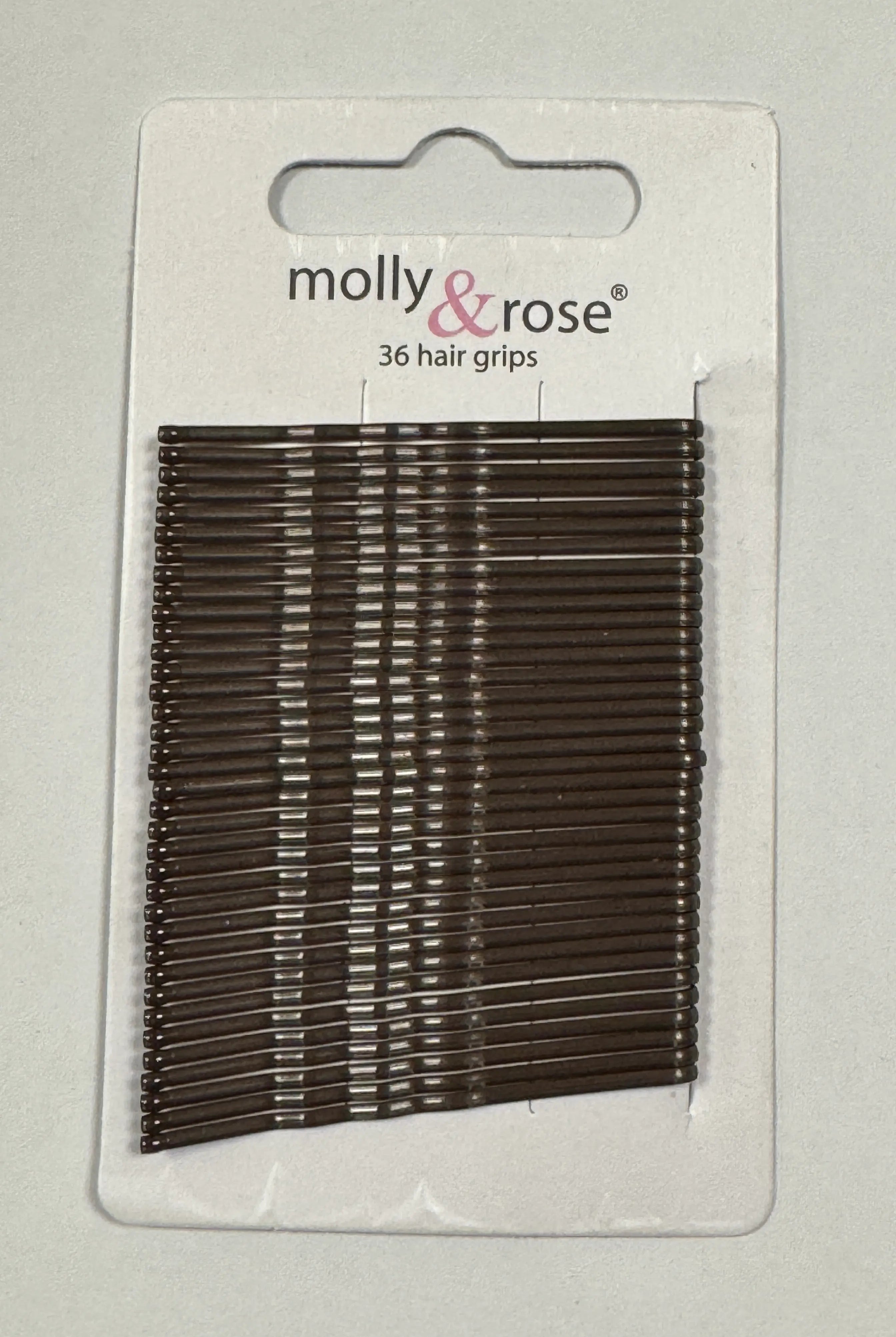 Eine Packung mit 36 braunen Haarklammern von Intermezzo, Produktname „Haarklemmen Intermezzo 7492 Molly“, abgebildet auf einer weißen Kartonrückseite.
