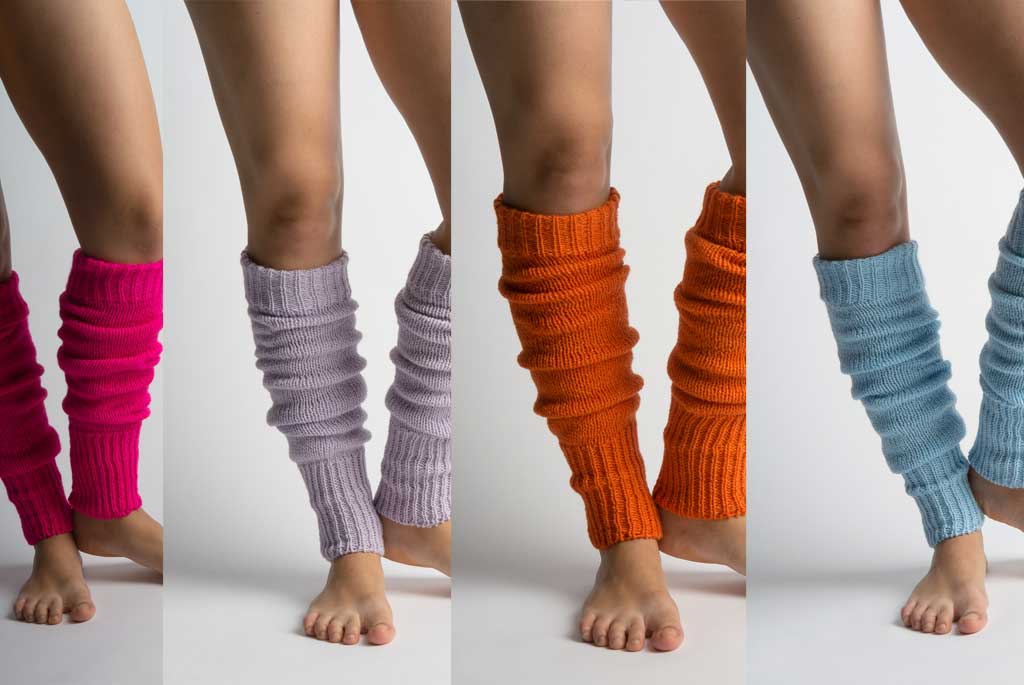 Vier Paar Beine mit Stulpen in unterschiedlichen Farbe: hellblau, orange, flieder und altrosa. Die Stulpen haben keinen Steg