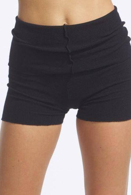Eine Person trägt die Wärmehose TempsDanse Jordan, schwarze Rippshorts mit Rollbund. Der Fokus liegt auf der Körpermitte und den Beinen, wodurch die perfekte Passform betont wird. Der Hintergrund ist schlicht weiß.