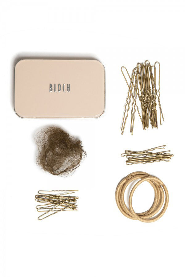 Eine beige Blechdose mit der Aufschrift „Hair Kit Bloch A0801“ der Marke Bloch ist von Haaraccessoires umgeben, darunter ein braunes Haarnetz, mehrere Haarnadeln, Haarklammern und drei beige Haargummis. Die Artikel sind ordentlich um die Dose herum angeordnet.