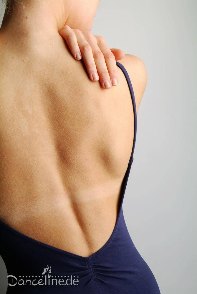 Eine Person, von hinten betrachtet, trägt einen Ballettanzug Bloch L5417 Royal mit Spaghetti-Träger. Die Hand der Person ruht auf ihrem oberen Rücken und betont so ihren schlanken und muskulösen Körperbau. Der Hintergrund ist schlicht und hell. In der unteren linken Ecke ist das Logo „Danceline.de“ zu sehen.