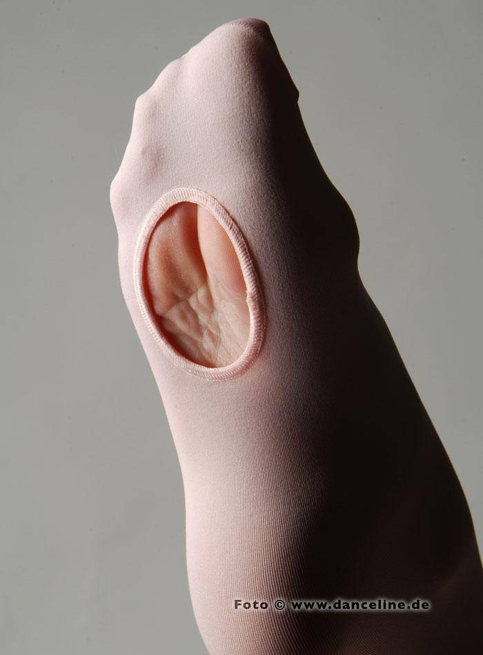 Nahaufnahme eines Fußes, der eine pfirsichfarbene Capezio Ballettstrumpfhose 1818 B-Tight mit einer ovalen Öffnung am Fußgewölbe trägt, die einen Teil der Sohle freigibt. Der Hintergrund ist schlicht und neutral. In der unteren rechten Ecke ist teilweise eine URL „www.danceline.de“ sichtbar.