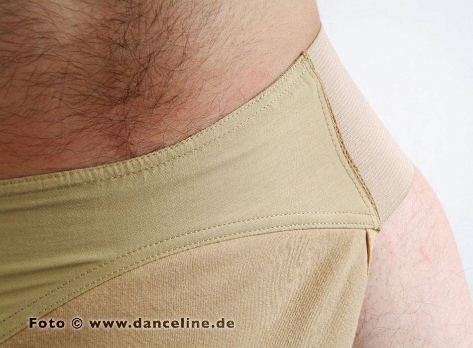 Nahaufnahme eines Mannes, der den Tanzslip Capezio Suspensorium (Modell 5930 SusiB) in Beige trägt. Der Bund und der glatte Stoff sind deutlich zu erkennen, ebenso Teile des Unterleibs und des Beinbereichs der Person. Das Foto enthält in der unteren linken Ecke ein Wasserzeichen mit dem Text „Foto © www.danceline.de“.