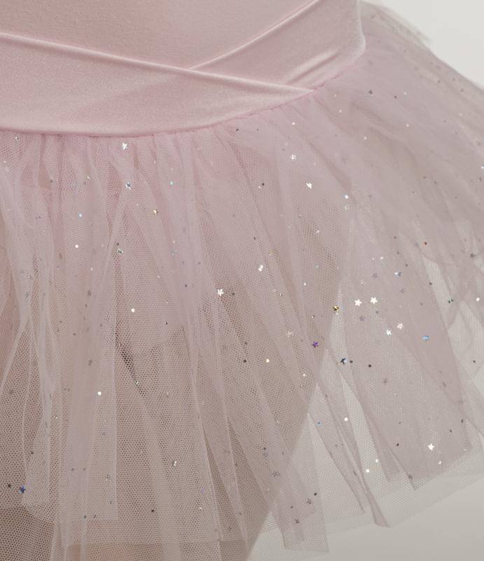 Eine Nahaufnahme des zartrosa Capezio Kinder-Ballettanzugs 9814C Jadica mit einer schimmernden, sternenbesetzten Tüllauflage. Der zarte Stoff des Tüllrocks ist mit kleinen, funkelnden Pailletten verziert, die ihm ein magisches und ätherisches Aussehen verleihen.