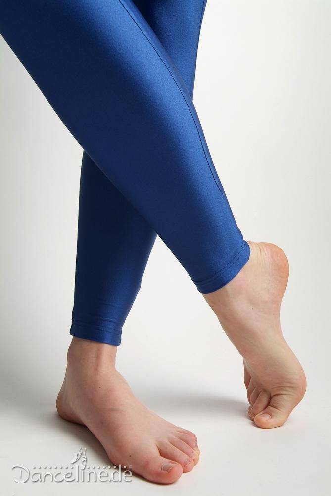 Nahaufnahme der Beine und Füße einer Person, die glänzende blaue Leggings trägt. Die Person steht mit einem Fuß flach auf dem Boden und dem anderen Fuß auf den Zehen und präsentiert ihren Danceries Ganzanzug G18L Sim EL. Der Hintergrund ist schlicht weiß, unten links ist „Danceline.de“ zu sehen.