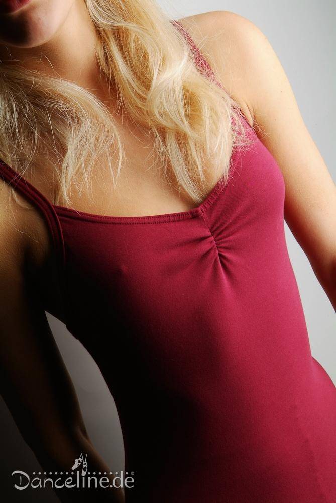 Eine Person mit langen blonden Haaren trägt den ärmellosen, taillierten Ballettanzug Danceries T16 Linda der Marke Danceries und strahlt sowohl Stil als auch Komfort aus. Der Hintergrund wechselt sanft von Hellgrau zu Dunkelgrau, während das Foto den Oberkörper der Person deutlich hervorhebt und so die Eleganz hervorruft, die mit einem Ballettanzug einhergeht.