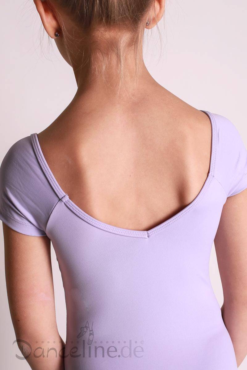 Von hinten ist ein junges Mädchen zu sehen, das einen hellvioletten Dance Line Kinder Ballettanzug Mirella M578C mit Rüschen und Flügelärmeln trägt. Ihr Haar ist zu einem ordentlichen Knoten hochgebunden. Der Hintergrund ist in einer schlichten hellen Farbe gehalten und der untere Teil eines Wasserzeichens mit der Aufschrift „Dandeline.de“ ist sichtbar.
