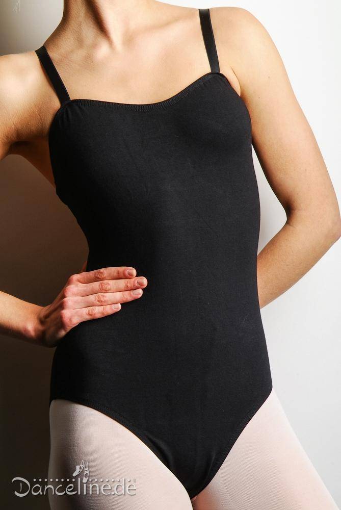 Eine Person in einem schwarzen Ballettanzug RochValley CMajor und hellen Strumpfhosen steht vor einem schlichten Hintergrund, die linke Hand ruht auf der Hüfte. In der unteren linken Ecke des Bildes ist das Logo „Dancelinede“ zu sehen. Für einen eleganten Touch hat sie sich für ein Obertrikot mit Spaghettiträger der Marke Roch Valley entschieden.