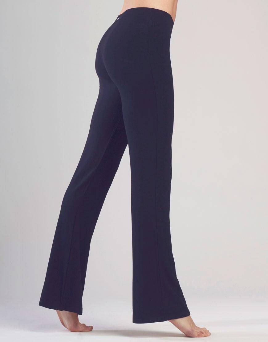 Eine Person steht auf den Zehenspitzen mit ausgestreckten Armen und trägt eine hoch taillierte, gerade geschnittene schwarze Jazzhose Temps Danse Luna von Temps Danse. Der neutrale Hintergrund betont die Passform und Länge der Hose und die Person wird von hinten gezeigt.