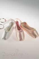 Drei Ballettschuh-Schlüsselanhänger in Pastellfarben (weiß, rosa und pfirsich) sind auf einer weißen Oberfläche abgebildet. Die **Mini-Spitzenschuh-Anhänger SoDanca KCE01 Minipoint**