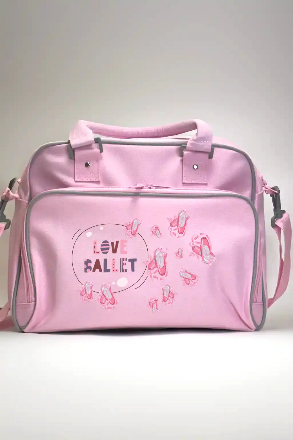 Die Kinder-Balletttasche Danceline Love Ballet von Dance Line ist eine rosafarbene Balletttasche mit kleinen Ballettschuhen und dem Spruch „Love Ballet“ in Lila und Rosa. Sie verfügt über zwei Griffe, einen abnehmbaren Schultergurt und graue Akzente an den Rändern.