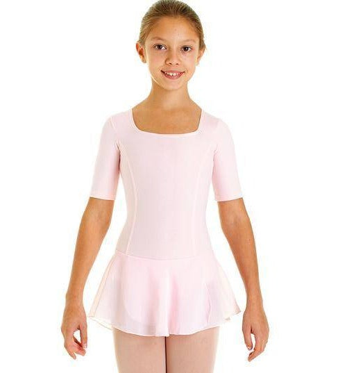 Ein junges Mädchen steht lächelnd in einem hellrosa Kinder-Ballettanzug Intermezzo 3058 von Intermezzo. Sie hat eine ordentliche Duttfrisur und ihre Arme hängen entspannt an ihren Seiten. Das Ballettkostüm mit Prinzessinnen-Nähten ist ein kurzärmeliger Turnanzug mit angenähtem Rock. Der Hintergrund ist schlicht weiß.